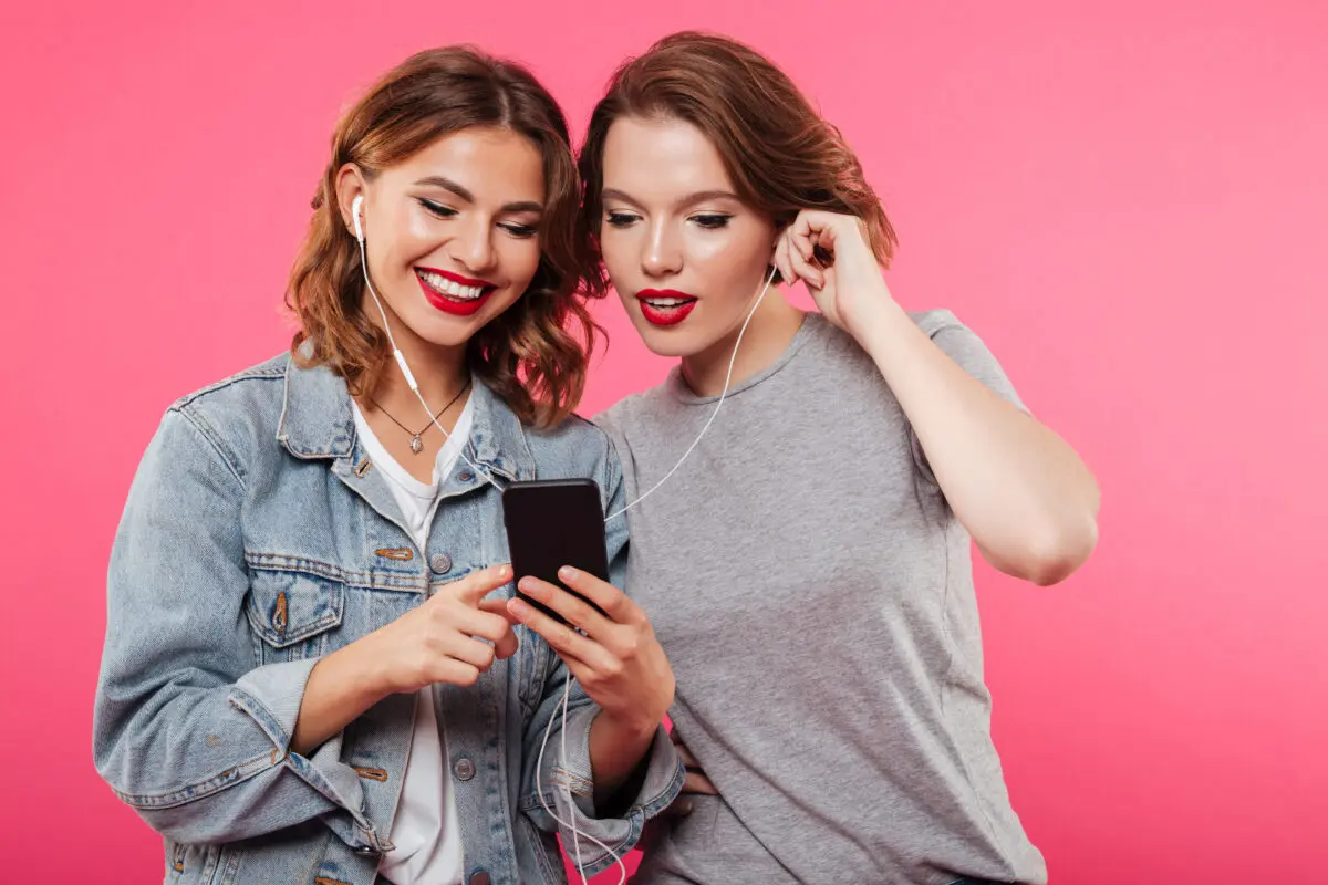 Duas mulheres escutando musica fundo rosa Desperta Debora