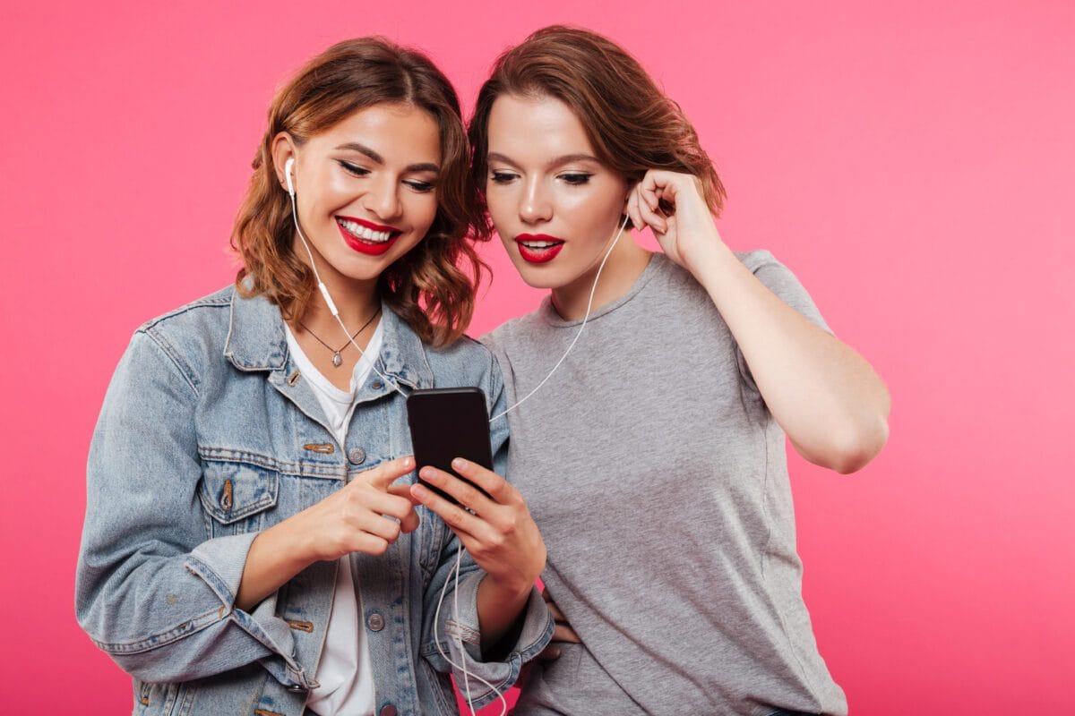 Duas mulheres escutando musica fundo rosa Desperta Debora