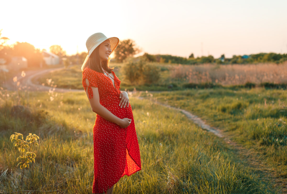 Gestante de chapeu e vestido vermelho no campo Desperta Debora