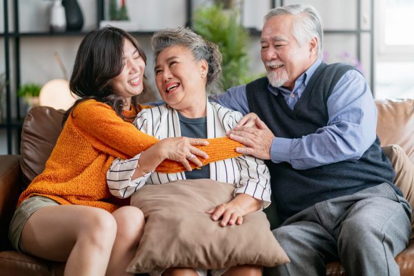 happiness asian family candid of daughter hug grandparent mother farther senior elder cozy relax on sofa couch surprise visiting in living room at hometogether hug cheerful asian family at