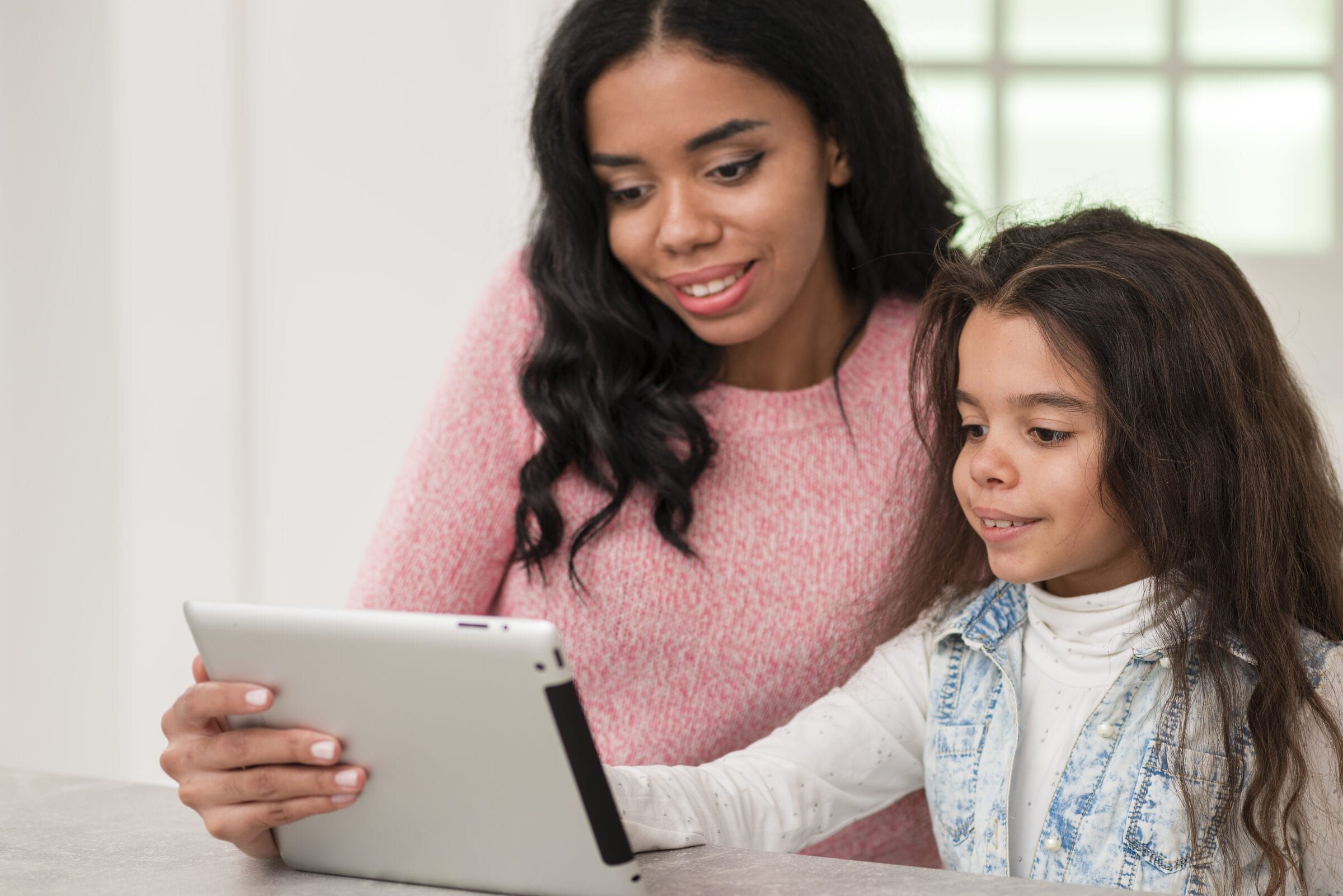 Mãe e filha sorridentes usando o tablet Desperta Débora