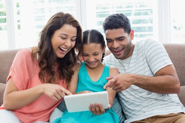 Parents and daughter using digital tablet in living room