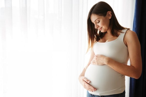 portrait of a happy pregnant woman touching her belly