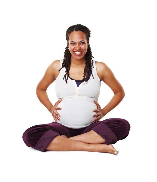 portrait of a pregnant mother or woman in happy sitting and holding her baby bump isolated on a white background black female excited smile and ready for a newborn child alone with cross