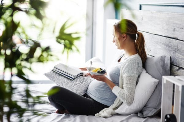 pregnant woman reading a book at bedroom